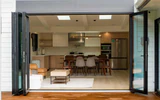 Open bi-folding glass doors with panels folded to either side of a kitchen and living space